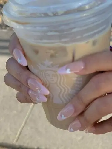 Long almond nails with baby pink French tips and white accent hearts for a chic and romantic Valentine’s Day nail design.