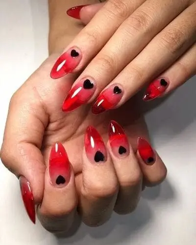 Chic red jelly nails with dainty black hearts for a sophisticated and alt Valentine's Day look. Trendy design perfect for an edgy yet romantic vibe.