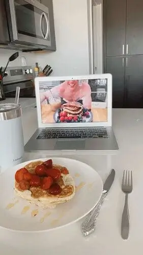 Romantic long-distance Valentine's Day idea of cooking breakfast together on video chat, featuring heart-shaped pancakes, cozy coffee mugs, and smiles across screens.